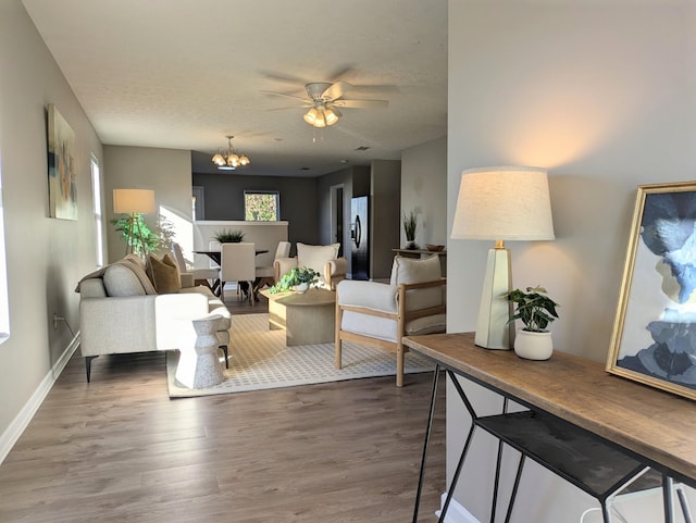 living room with dark hardwood / wood-style floors, ceiling fan with notable chandelier, and a textured ceiling