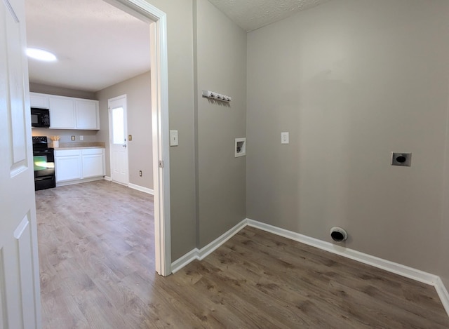 laundry area with electric dryer hookup, hookup for a washing machine, wood-type flooring, and a textured ceiling