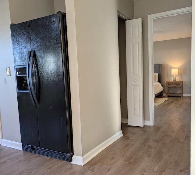 kitchen with hardwood / wood-style flooring and black fridge with ice dispenser