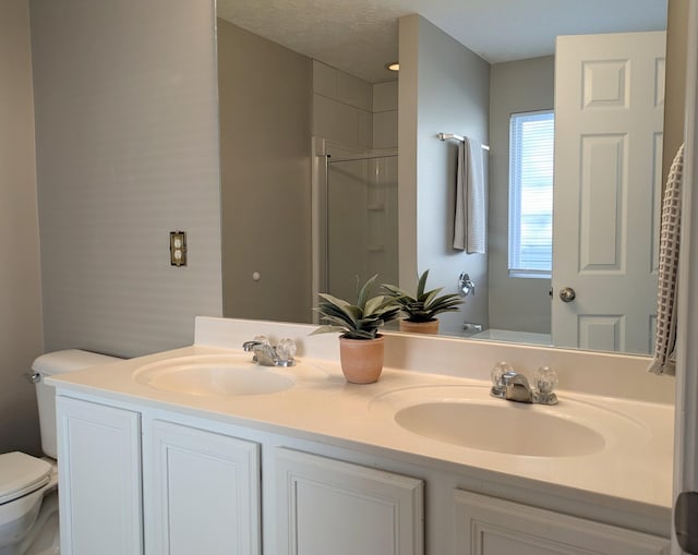 bathroom with walk in shower, vanity, toilet, and a textured ceiling