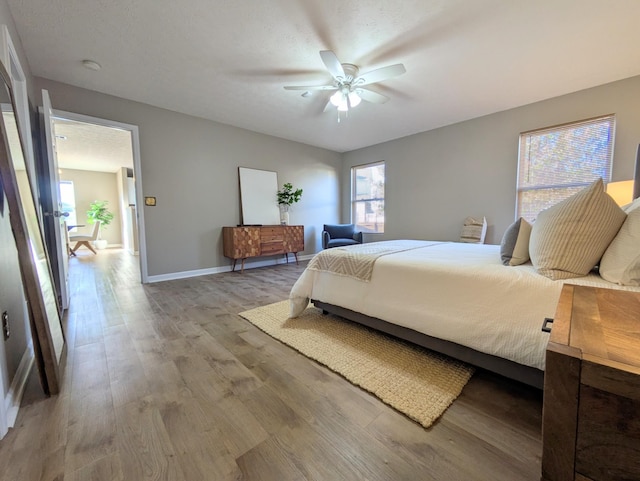 bedroom with ceiling fan, a textured ceiling, and light wood-type flooring