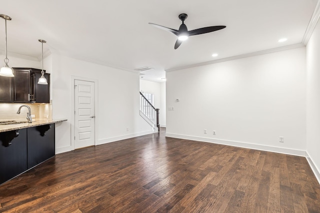 unfurnished living room with sink, dark wood-type flooring, ornamental molding, and ceiling fan