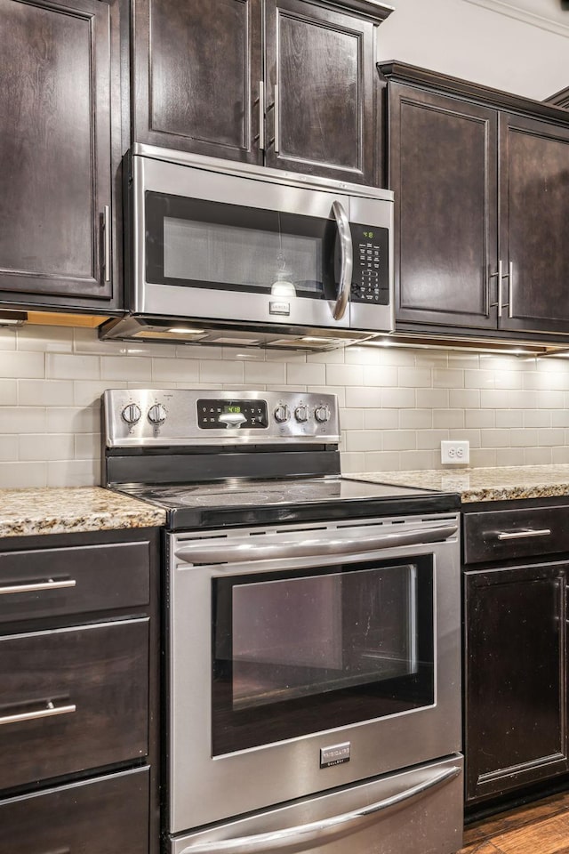 kitchen featuring dark brown cabinetry, tasteful backsplash, light wood-type flooring, stainless steel appliances, and light stone countertops