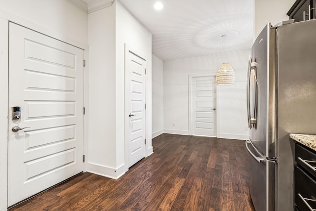 kitchen featuring hanging light fixtures, dark wood-type flooring, stainless steel fridge, and light stone countertops