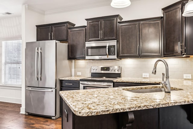 kitchen featuring appliances with stainless steel finishes, sink, ornamental molding, light stone counters, and dark brown cabinets