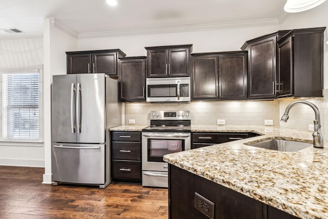 kitchen with sink, stainless steel appliances, crown molding, light stone countertops, and dark wood-type flooring