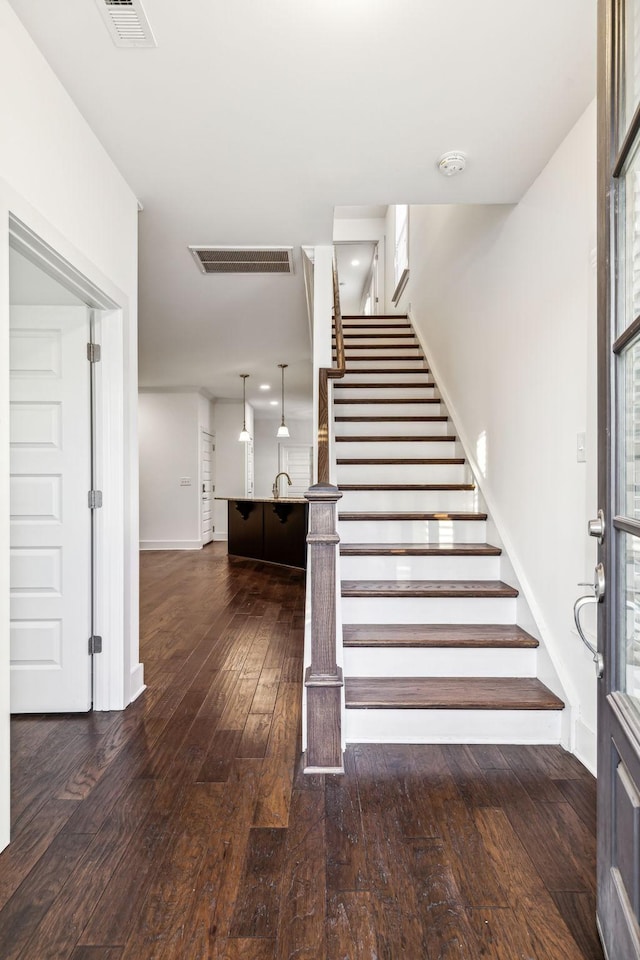 stairs featuring hardwood / wood-style floors and sink