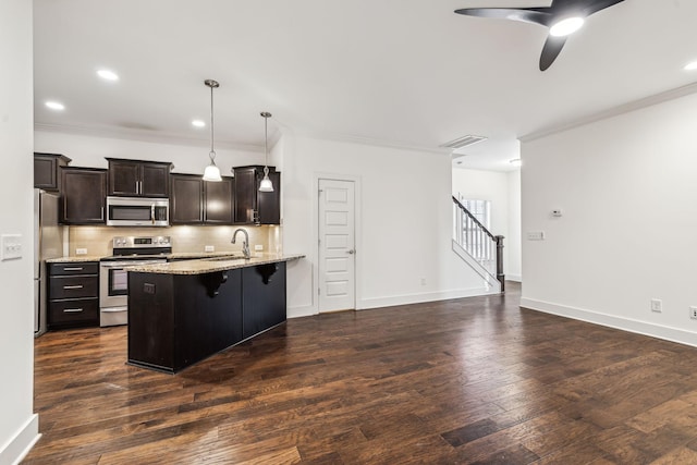 kitchen featuring pendant lighting, appliances with stainless steel finishes, a kitchen breakfast bar, dark hardwood / wood-style floors, and light stone countertops