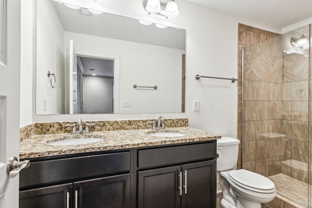 bathroom with vanity, tiled shower, and toilet