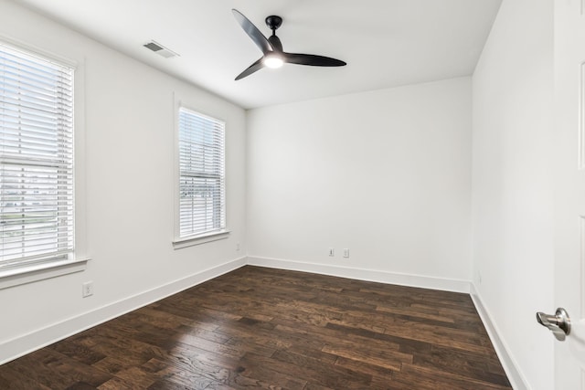 empty room with a wealth of natural light, dark wood-type flooring, and ceiling fan