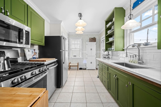 kitchen with ornamental molding, appliances with stainless steel finishes, sink, and decorative light fixtures