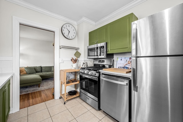 kitchen featuring green cabinets, light tile patterned flooring, ornamental molding, and appliances with stainless steel finishes