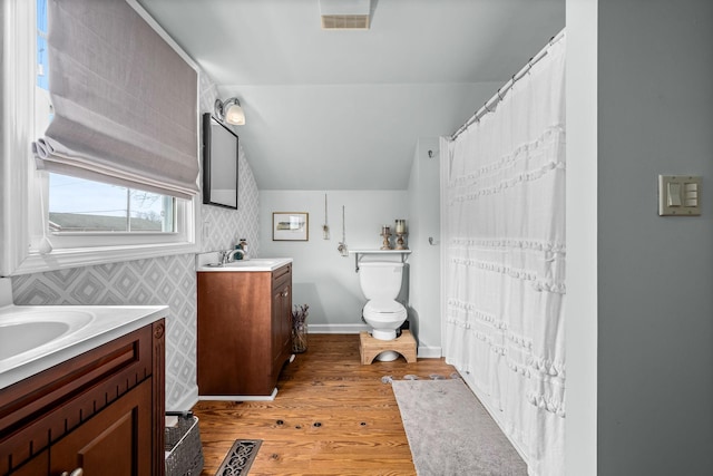 bathroom featuring vanity, hardwood / wood-style floors, vaulted ceiling, and toilet