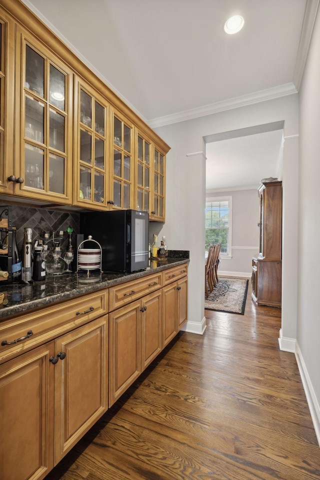 kitchen with crown molding, dark stone counters, dark wood-type flooring, and tasteful backsplash