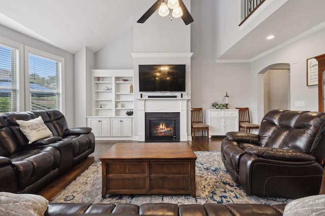 living room with wood-type flooring, ornamental molding, ceiling fan, and high vaulted ceiling