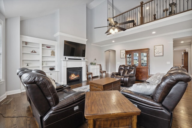 living room featuring dark hardwood / wood-style floors, ceiling fan, and a towering ceiling