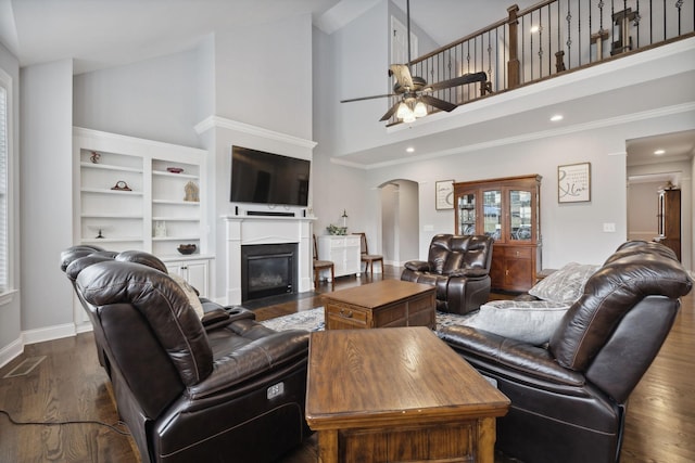 living room with ceiling fan, a towering ceiling, and dark hardwood / wood-style flooring