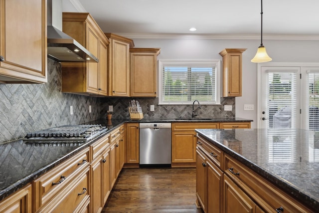 kitchen with pendant lighting, sink, dark stone countertops, stainless steel appliances, and wall chimney range hood