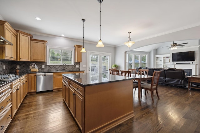 kitchen with dark stone counters, hanging light fixtures, a center island, stainless steel appliances, and dark wood-type flooring