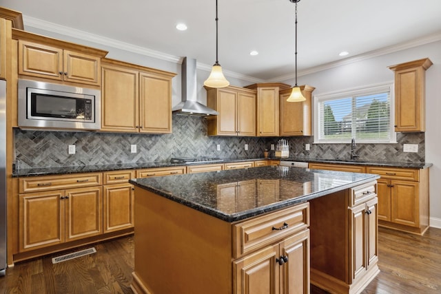 kitchen featuring wall chimney range hood, a kitchen island, hanging light fixtures, and appliances with stainless steel finishes