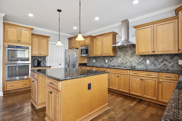 kitchen with pendant lighting, wall chimney range hood, appliances with stainless steel finishes, a center island, and dark stone counters