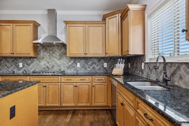 kitchen with sink, dark stone countertops, ornamental molding, stainless steel appliances, and wall chimney range hood