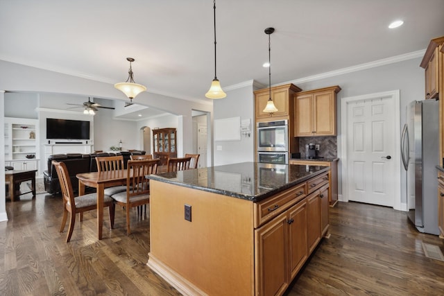 kitchen featuring hanging light fixtures, stainless steel appliances, a center island, and dark stone counters