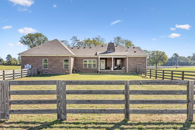 view of front of house with a rural view and a front lawn