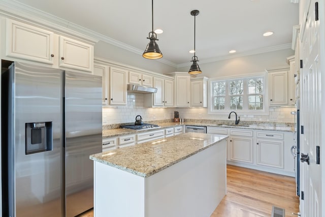 kitchen with appliances with stainless steel finishes, pendant lighting, sink, a center island, and light stone counters