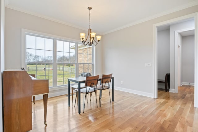 dining space featuring crown molding, a chandelier, and light hardwood / wood-style floors