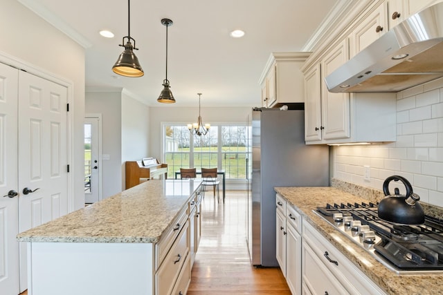 kitchen featuring light stone counters, hanging light fixtures, ornamental molding, and stainless steel gas cooktop