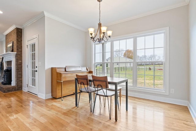 dining space with hardwood / wood-style floors, a fireplace, ornamental molding, and a chandelier