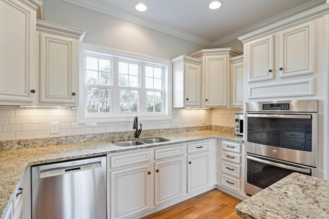 kitchen featuring sink, decorative backsplash, ornamental molding, light stone counters, and stainless steel appliances