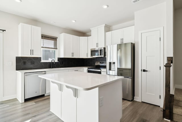 kitchen with a kitchen breakfast bar, stainless steel appliances, a center island, and white cabinets