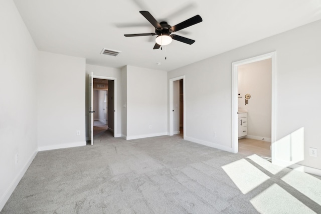 unfurnished bedroom with ceiling fan, light colored carpet, and ensuite bath