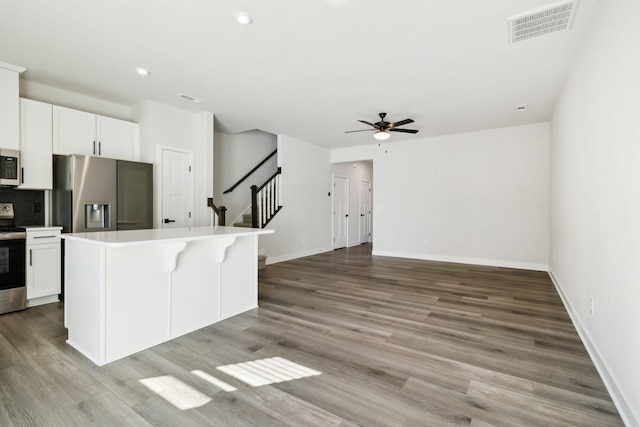 kitchen with white cabinetry, a kitchen island, light hardwood / wood-style flooring, and appliances with stainless steel finishes