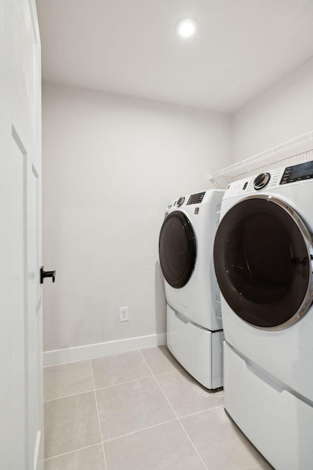 clothes washing area featuring washing machine and clothes dryer and light tile patterned floors