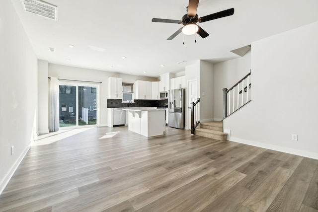 kitchen featuring a breakfast bar area, appliances with stainless steel finishes, white cabinetry, a center island, and light wood-type flooring