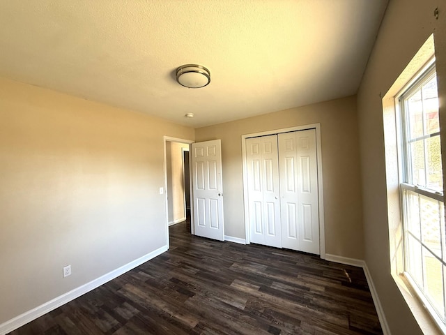 unfurnished bedroom with dark wood-type flooring, a closet, and a textured ceiling