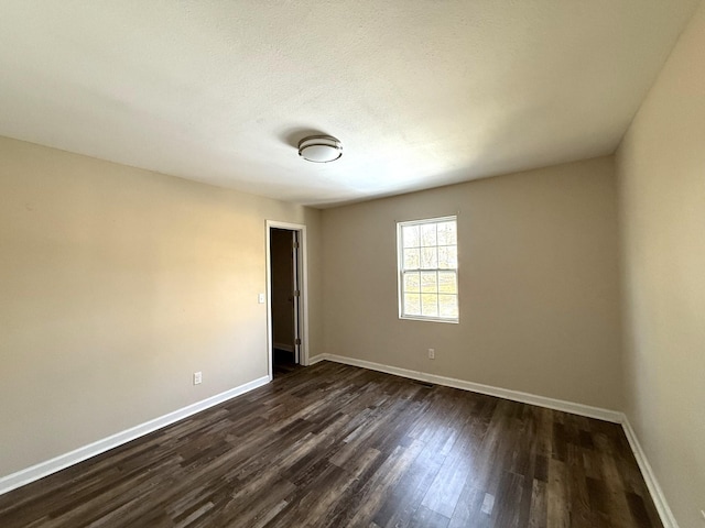 unfurnished room featuring dark wood-type flooring and a textured ceiling