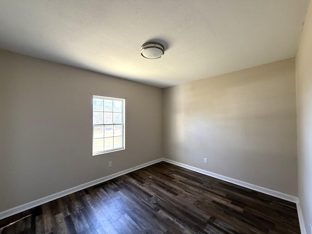 unfurnished room featuring dark wood-type flooring and a textured ceiling