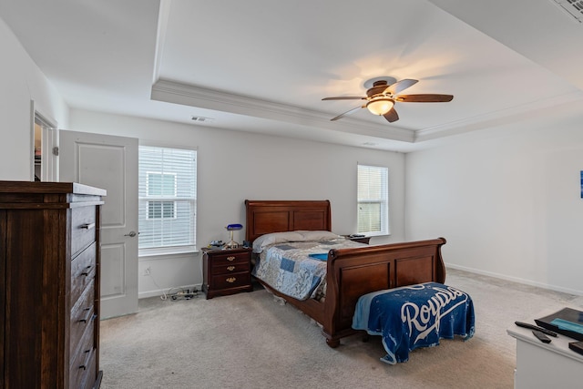 bedroom featuring ceiling fan, ornamental molding, a tray ceiling, and light carpet