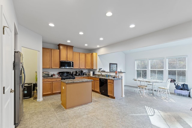 kitchen with sink, dark stone countertops, a center island, black appliances, and kitchen peninsula