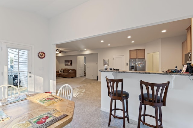 kitchen featuring stainless steel refrigerator with ice dispenser, light stone countertops, and ceiling fan