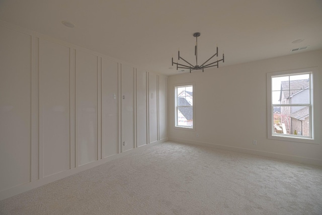 spare room featuring a chandelier and carpet floors