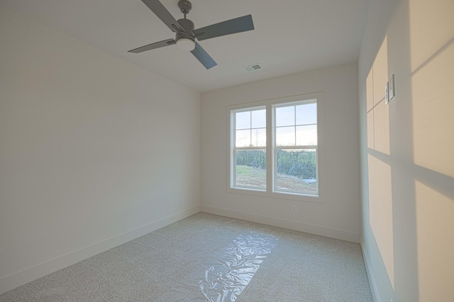 spare room with baseboards, ceiling fan, visible vents, and light colored carpet