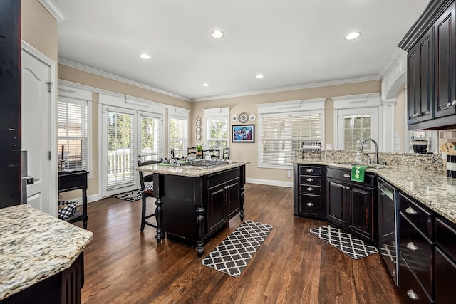 kitchen with sink, crown molding, light stone countertops, and a kitchen island