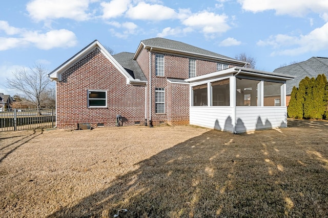 rear view of house featuring a sunroom and a lawn