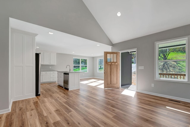 unfurnished living room with sink, light hardwood / wood-style flooring, and high vaulted ceiling