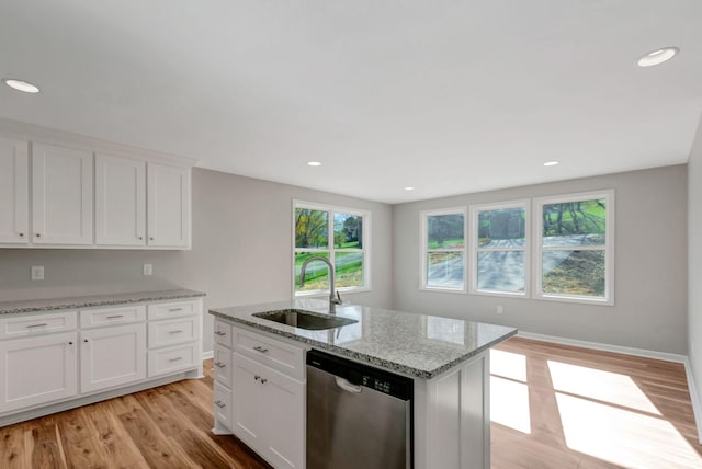 kitchen with an island with sink, sink, white cabinets, stainless steel dishwasher, and light stone counters